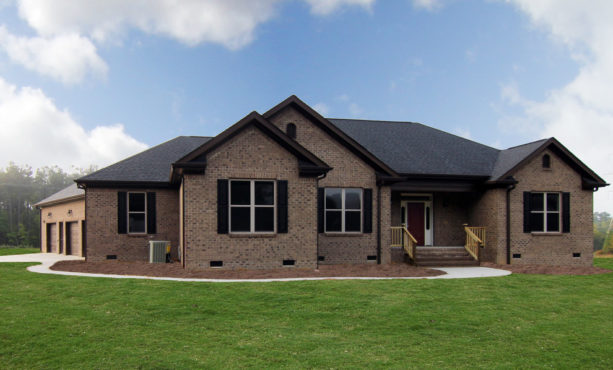 a transitional brown brick house with black shutters