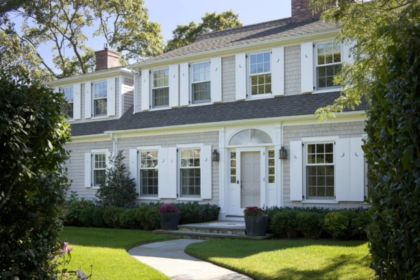 a classic traditional exterior with tan shingle siding and white shutters