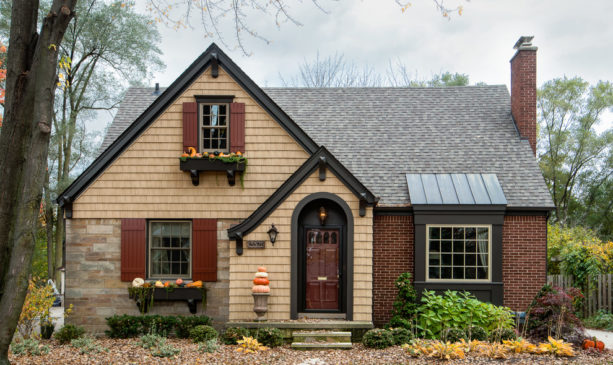 a traditional exterior with tan wall siding and red wood shutters