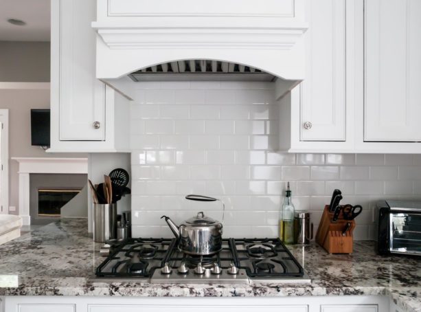 white subway tile backsplash and white grout that look contrast to the stove and countertop