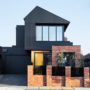 a contemporary house with black siding and red brick