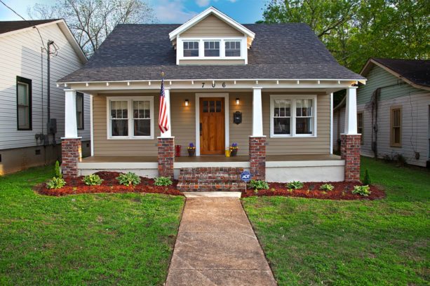 a craftsman-style house with tan siding and red brick columns