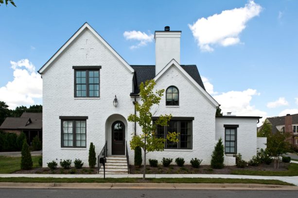 a white brick house with unique and prominent black top trim for the windows