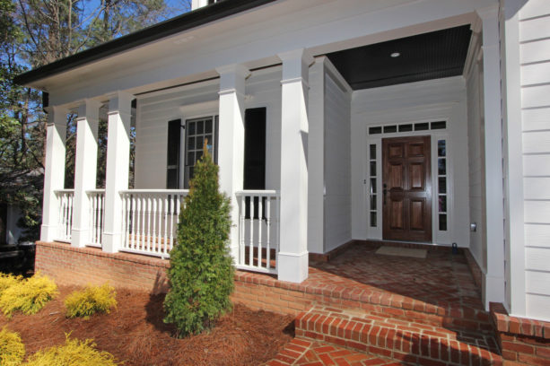 a white wall siding paired with red brick floor in a traditional exterior