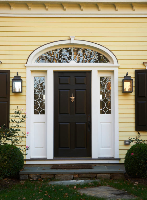 a black custom traditional front door with decorative transom and sidelights