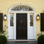 a black custom traditional front door with decorative transom and sidelights