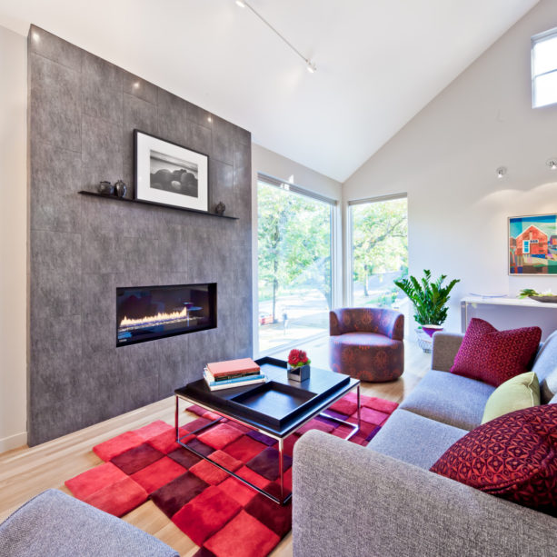 a grey living room with multi-tone red rug under the black coffee table