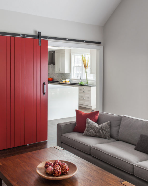 catchy red sliding door that separated a grey living room with the kitchen next to it