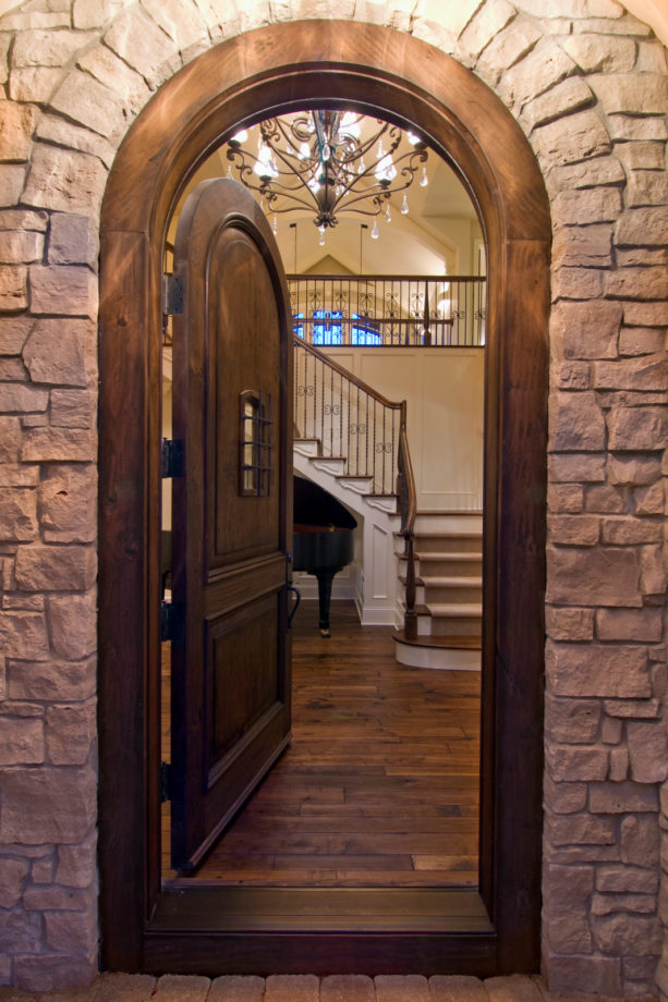 a traditional arched wooden front door with trim stained in the same color