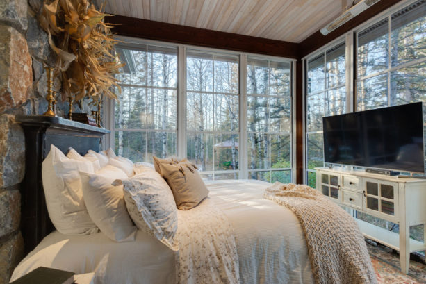 a sunroom with bed, complete with a TV placed right in front of the window