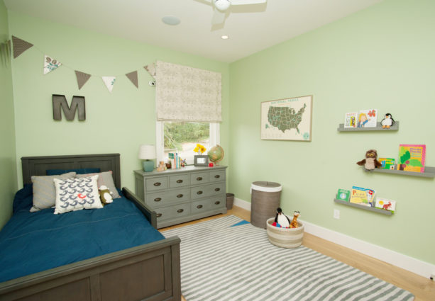 a boy bedroom with pastel green wall paint and grey furniture and decorations
