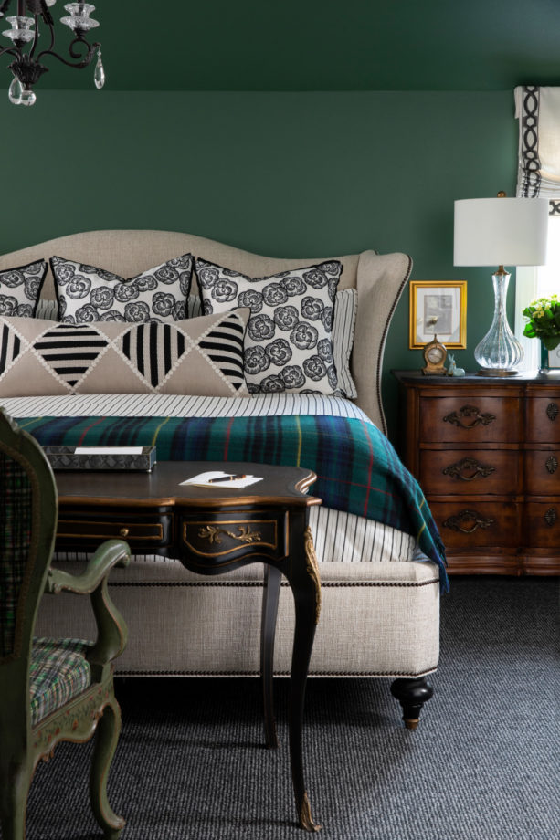 a rich-looking bedroom with dark green walls and dark gray carpet