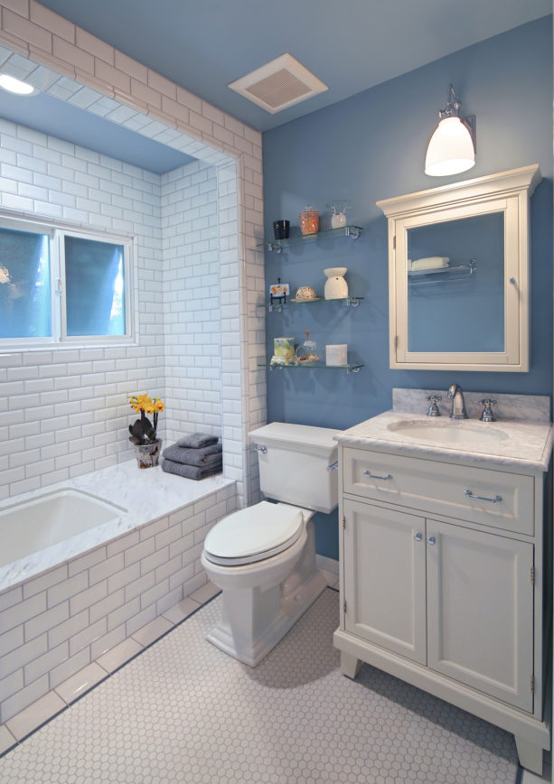 a small bathroom with white tiles and blue walls to create a cozy feeling