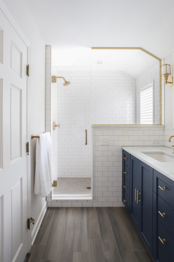 a small yet elegant bathroom with a navy blue cabinet and white tiles