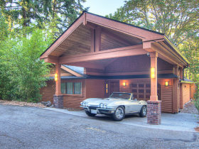 sizeable arts and crafts carport in front of a wooden siding garage