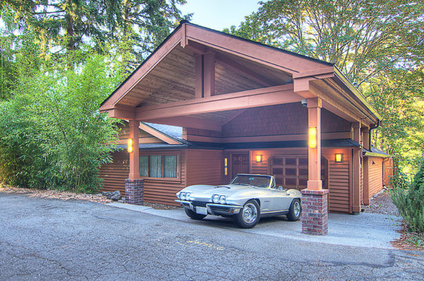 sizeable arts and crafts carport in front of a wooden siding garage