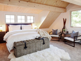 rustic attic bedroom with vaulted ceiling and slanted walls in a natural wood finish