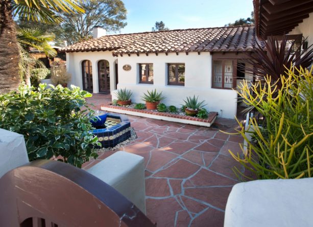 white spanish style home with a mediterranean red sandstone courtyard
