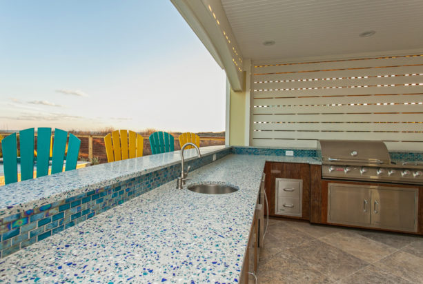 beach style outdoor l-shaped kitchen in the pool side with recycled glass countertops