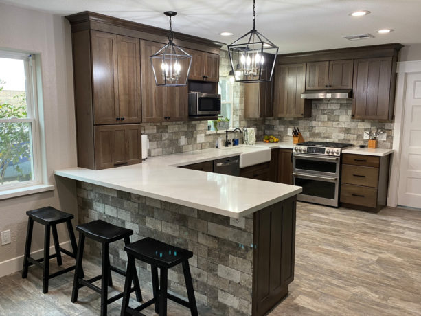 combination of gray travertine backsplash, white countertops kitchen color, and brown shaker cabinets to get cozy sensation