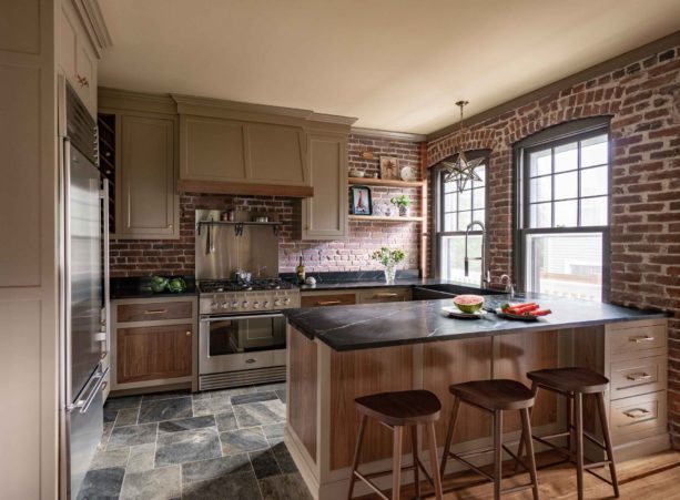 farmhouse style combination of brown shaker cabinets, black soapstone countertops and red-colored brick wall to add more texture in the kitchen