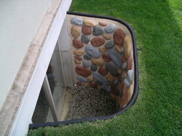 multicolored stone basement window well with black trim