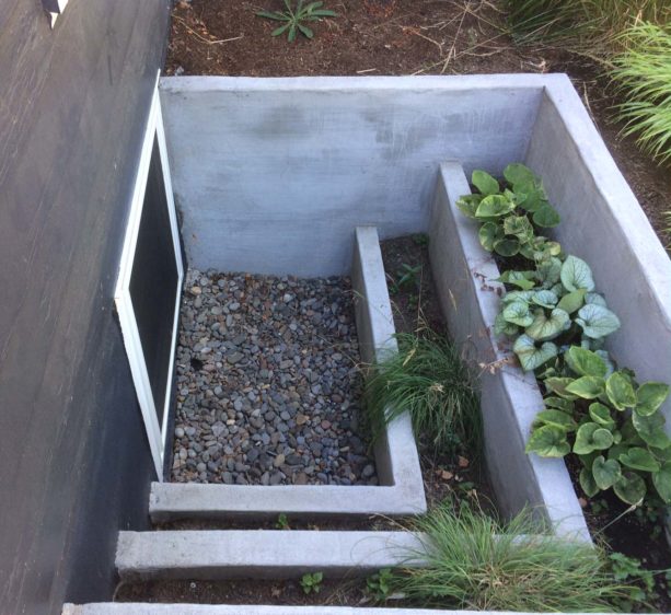poured concrete basement window well with tiered planter boxes