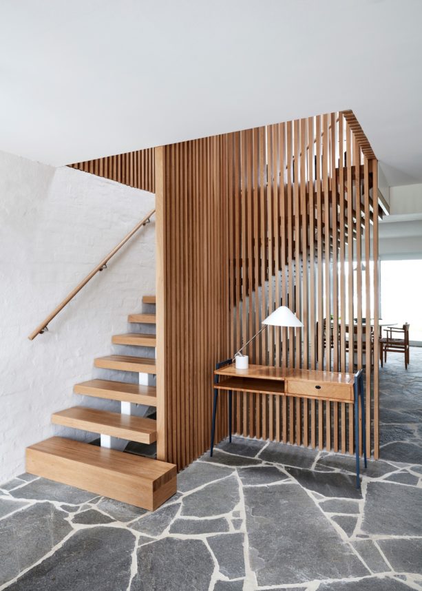 wooden staircase in an open and l-shaped design with a vertical wood slat wall