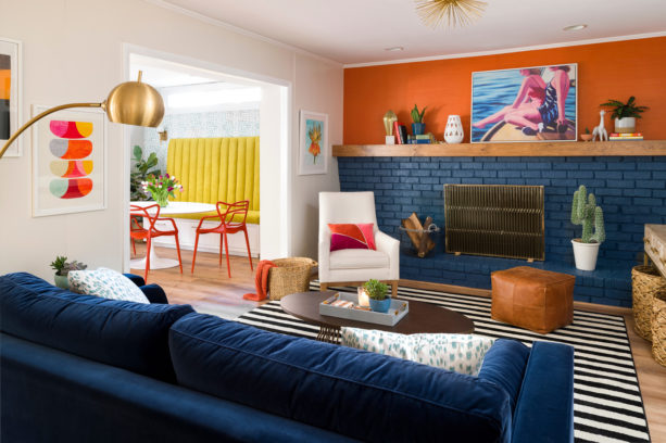 pairing of dark orange wall and navy blue brick fireplace and sofa in an eclectic living room