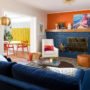 pairing of dark orange wall and navy blue brick fireplace and sofa in an eclectic living room