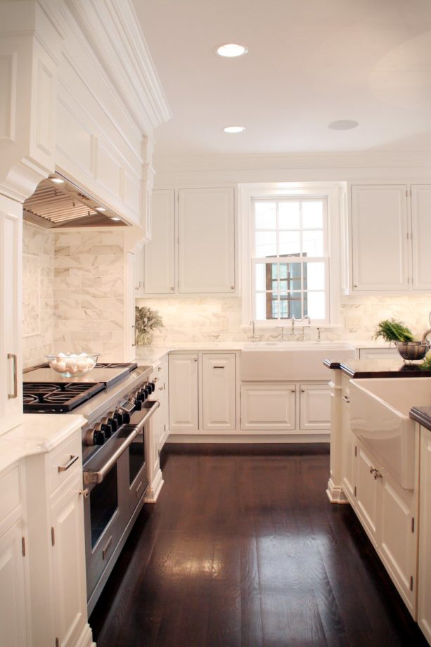 classic kitchen with white backsplash, counters, surround cabinets, and dark walnut hue floor