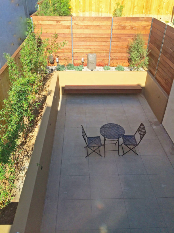 mediterranean concrete patio with raised planters in a small backyard