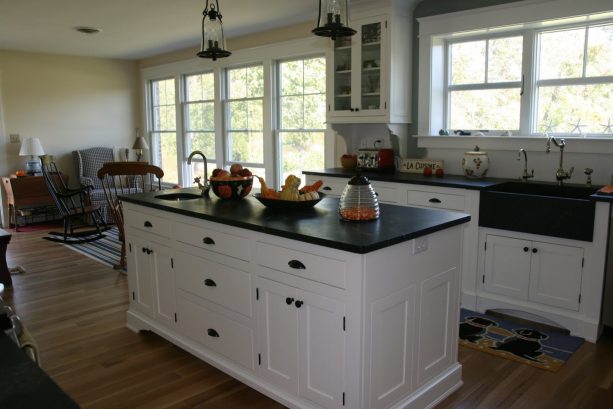white shaker cabinets with black hardware that matches the soapstone top