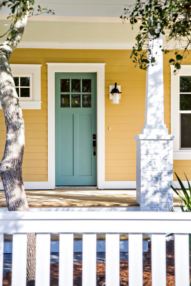 teal front door surrounded by yellow siding