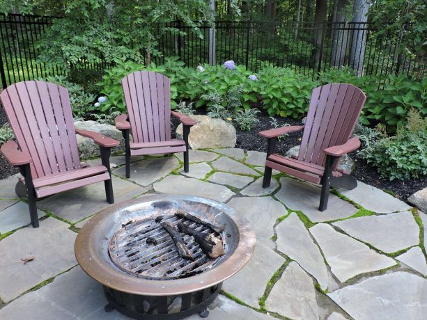 freestanding fire pit in a rustic landscape idea paired with wooden chairs
