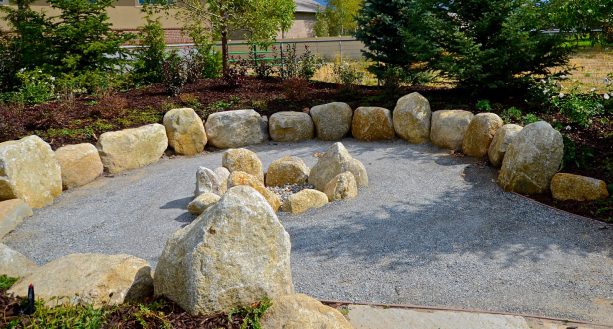 rustic fire pit surrounded by salt and pepper granite boulders
