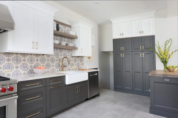 two-toned white and gray cabinets paired with floral patterned backsplash and white countertops