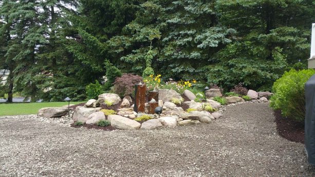 crushed rock landscaping with a mix of boulders and basalt column fountains in the center