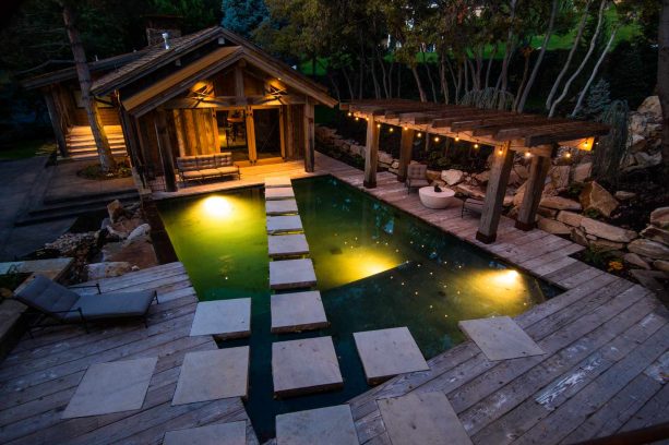 floating deck with a pergola made of weathered timber beside a pool