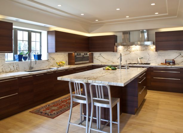 polished and dark kitchen cabinets that contrast the light calacatta gold marble backsplash and countertops