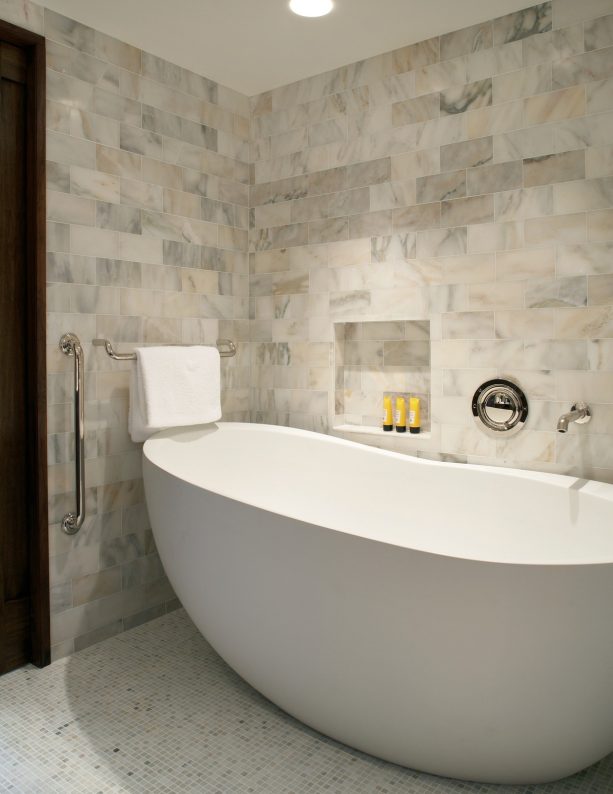 recessed niche in a marble wall next to a bathtub for shower gels
