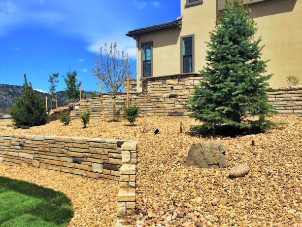 sloped yard with multiple levels filled with small rocks and decorative boulders