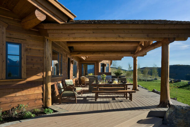 a lot of seating spaces on a log cabin porch that opens to a beautiful landscape