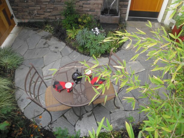 a small seating space in a townhouse patio with a water feature