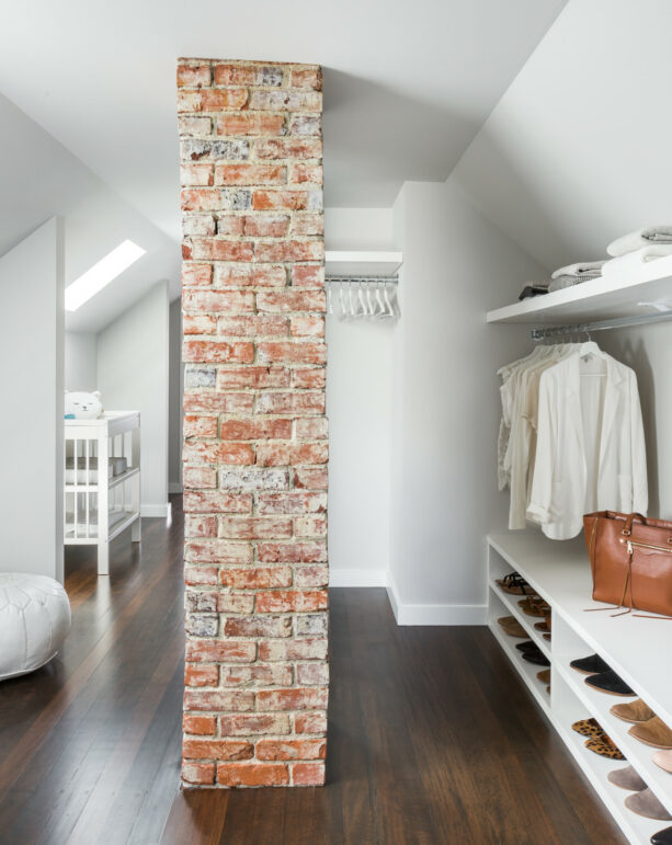 a brick column in the middle of a white attic closet