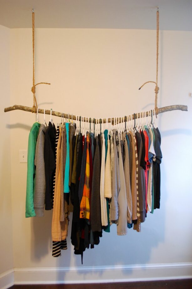 rustic styled hanging clothes rack from the ceiling made of a solid branch