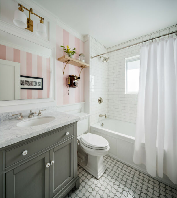 pink striped wallpaper as an accent wall in a soft gray bathroom